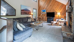 A living room with a sofa, coffee table, and fireplace. - Home with hot tubs, pools, tennis, pickleball, gym, fireplace, & game room (Black Butte Ranch)