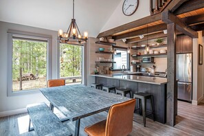 Una cocina moderna con una isla grande, taburetes de bar y una mesa de comedor con bancos.
