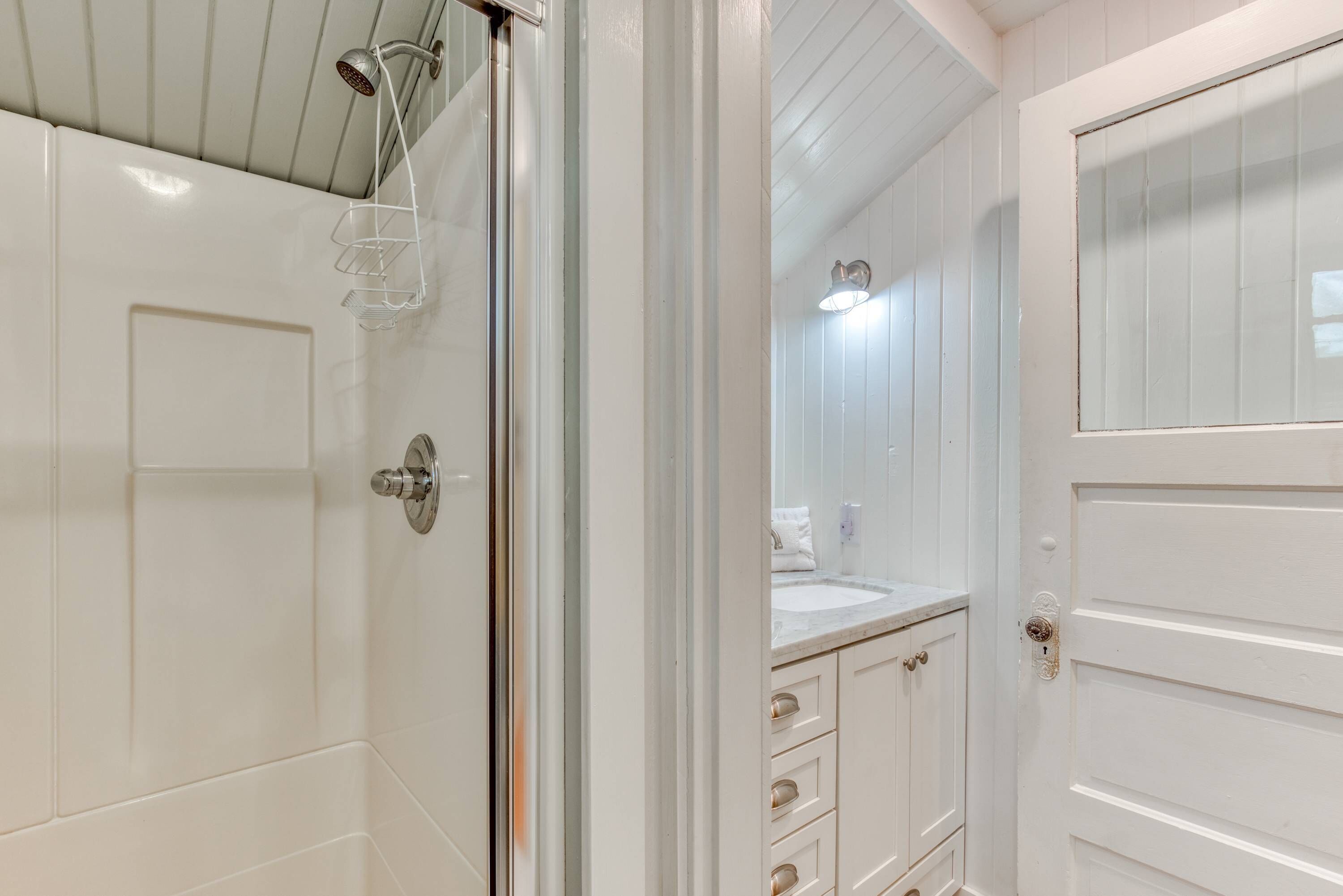 A bathroom with a shower, a sink, and a mirror.