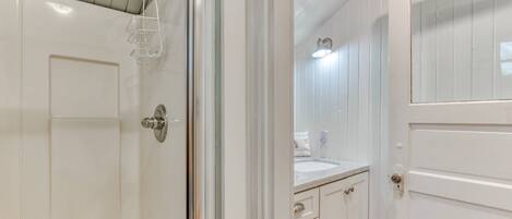 A bathroom with a shower, a sink, and a mirror.