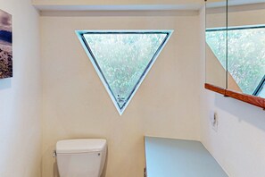Een badkamer met toilet, een drielingsraam en een houten trap.