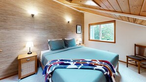 A bedroom with a bed, a nightstand, a chair, a window, and a skylight. - Tree-lined coastal home with wood fireplace, yard, W&D, & games - dog-friendly (Manzanita)