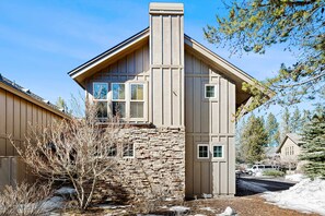 A two-story house with a stone foundation, a chimney, and a garage. - Luxurious home near the SHARC & Village with private hot tub, resort amenities (Sunriver)