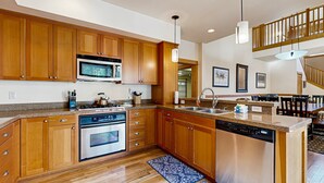 Una cocina moderna con armarios de madera, electrodomésticos de acero inoxidable y una isla central.