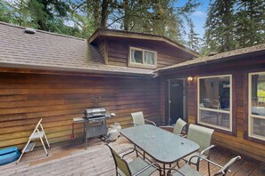 Une cabane en bois dotée d’une terrasse, d’un barbecue et d’une table avec des chaises.