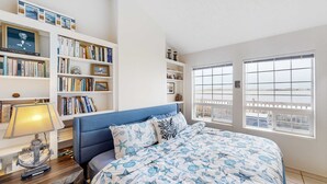 A bedroom with a bed, a bookshelf, a lamp, and a view through the window. - Waterfront Family Home with Beach Access - Dog-friendly (Waldport)