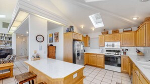 A modern kitchen with wooden cabinets, a central island, a refrigerator, an oven, and a microwave. - Waterfront Family Home with Beach Access - Dog-friendly (Waldport)
