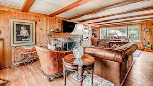 Een houten interieur met een open haard, een leren bank en een televisie.