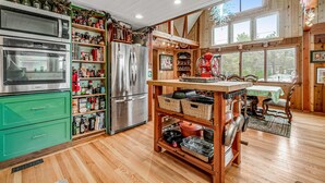Een keuken met een houten keukeneiland, roestvrijstalen apparatuur en een eethoek met een tafel en stoelen.