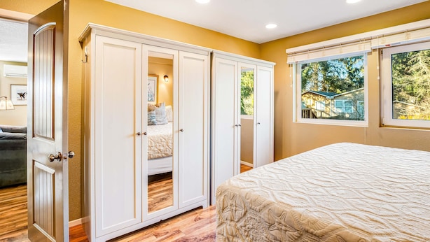 Un dormitorio con cama, armario y ventana con vistas a árboles.