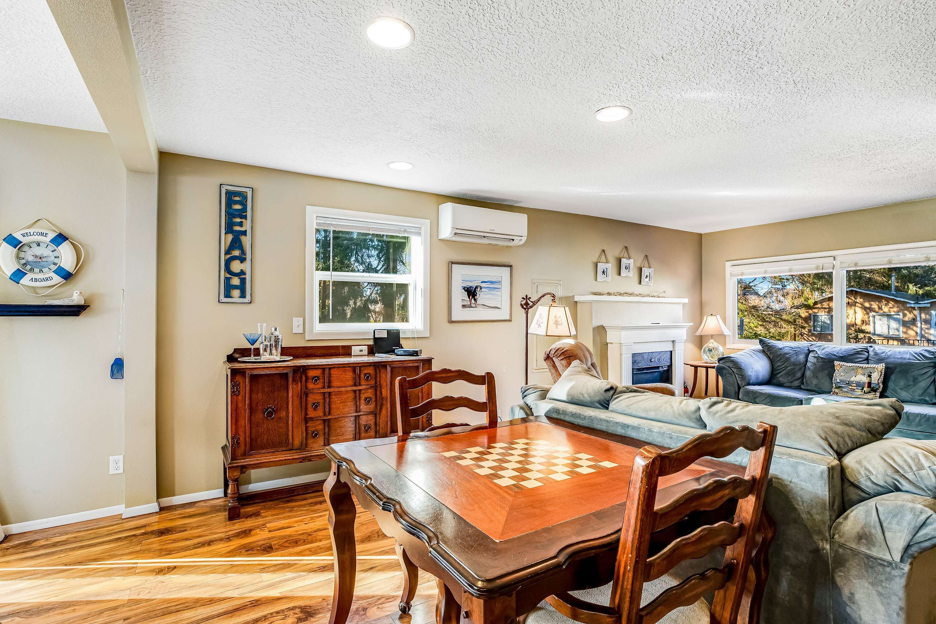 A dining area with a wooden table and chairs, a sofa, a fireplace, and a view of the outdoors.