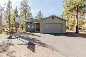 A residential property with a detached garage, a front porch, and a basketball hoop. - Sweet Sunriver Home with Private Hot Tub, Outdoor Space & Eight SHARC Passes (Sunriver)