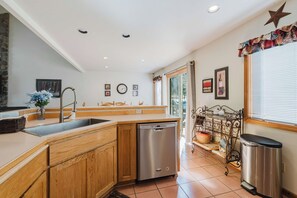 Una cocina con armarios de madera, lavavajillas de acero inoxidable y una ventana con vistas a árboles.