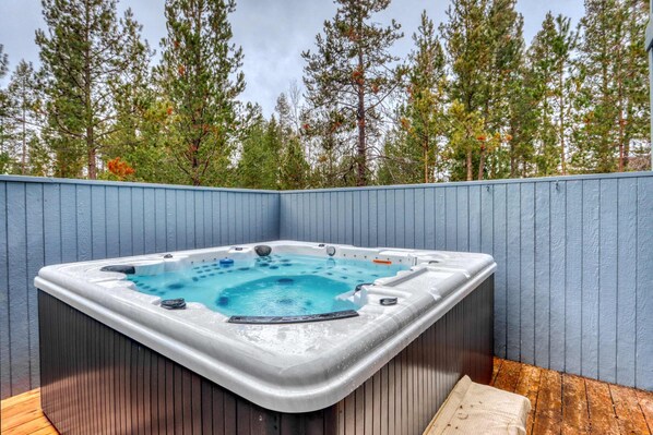 A hot tub in a corner with a wooden deck and a blue fence. - Sweet Sunriver Home with Private Hot Tub, Outdoor Space & Eight SHARC Passes (Sunriver)
