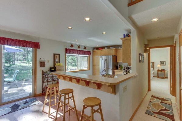 Una cocina con barra, taburetes de madera y vistas al exterior.