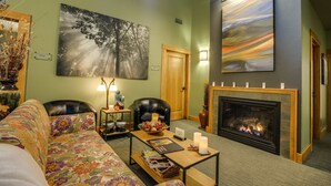 A living room with a fireplace, a sofa, a coffee table, and a painting on the wall.