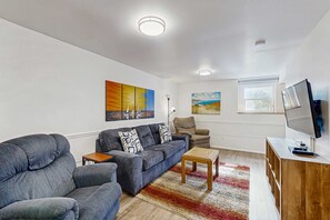 Un salon comprenant un canapé, un fauteuil, une table basse et un meuble pour la télévision.