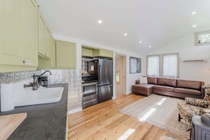 A modern kitchen with a sink, stove, and refrigerator, a brown leather sofa, and a patterned rug. - Cozy recreation home with full kitchen, washer & dryer, private lot and WIFI (Bend)