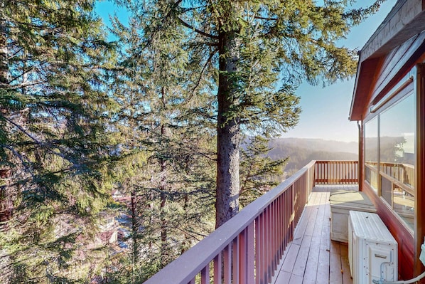 Eine Holzterrasse mit Blick auf einen Wald und ferne Berge.