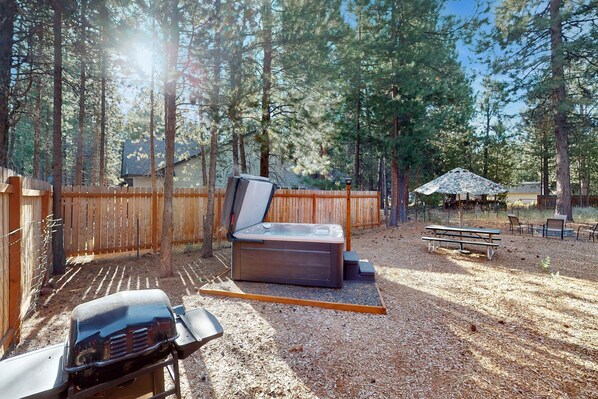 En baghave med jacuzzi, grill, picnicbord og parasol.