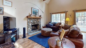 Una sala de estar con chimenea de piedra, televisor, sofá y una mesa de centro.
