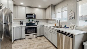 A modern kitchen with stainless steel appliances, white cabinetry, and a window providing a view. - Spacious condo, close to the river, with WiFi, streaming, washer&dryer (Florence)