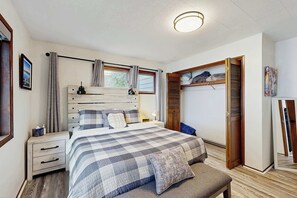 A bedroom with a bed, bedside tables, a wardrobe, and a window with curtains. - Lakefront dream with private hot tub, dock, kayaks, pedal boat & amazing views (Florence)