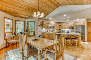 A spacious kitchen with wooden cabinets, a dining area with a large table and chairs, and a ceiling with wooden beams.