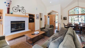 Amplia sala de estar con chimenea, un sofá, una mesa de centro y un comedor con muebles de madera.