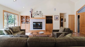 Amplia sala de estar con chimenea, dos sofás, una mesa de centro y una estantería.