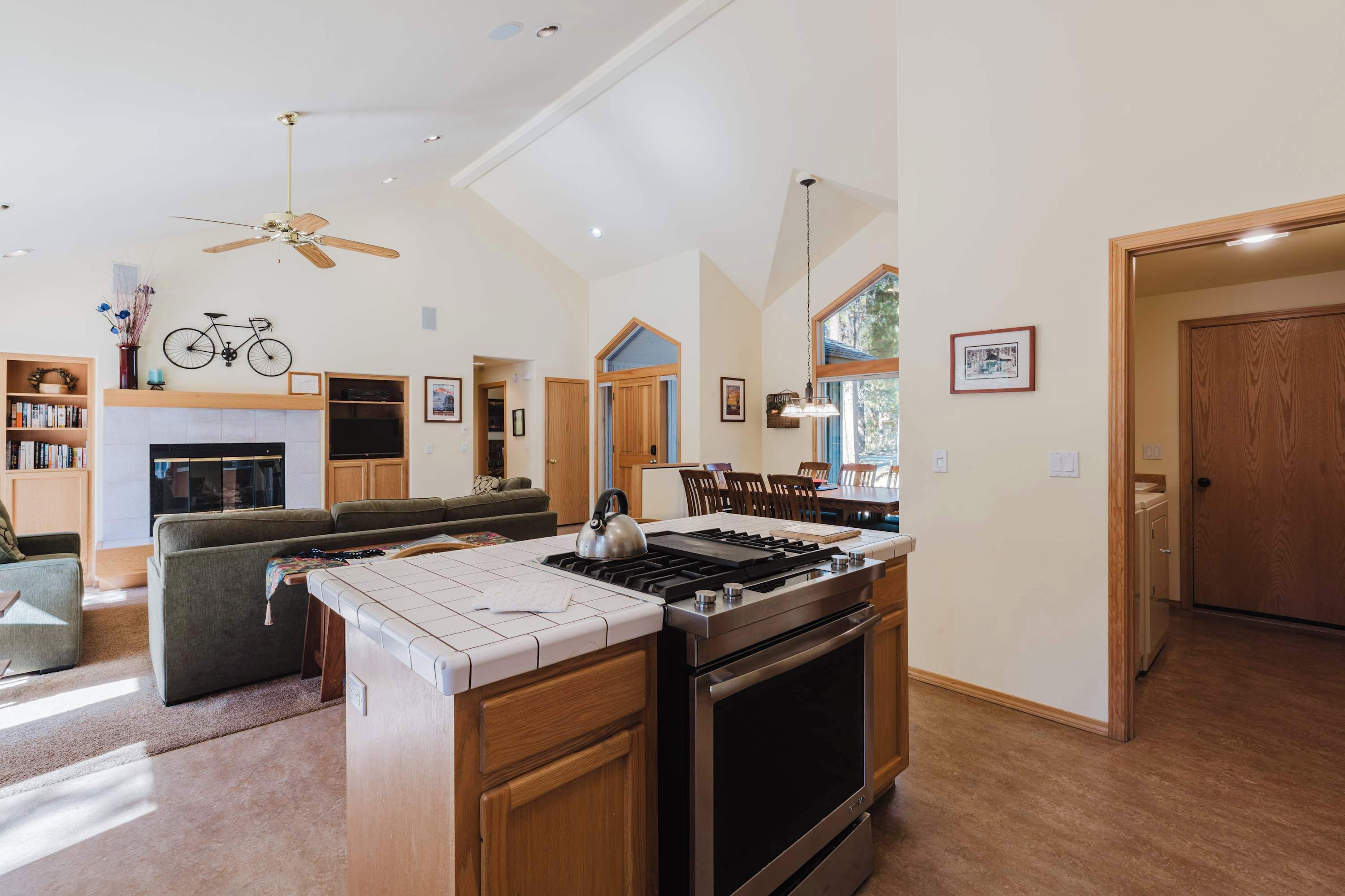 A spacious kitchen with a central island, a dining area with wooden chairs, and a living room with a sofa and a fireplace.