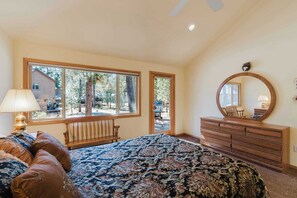 Ein Schlafzimmer mit einem Bett, einem Schminktisch, einer Bank und einem großen Fenster.