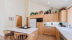 Una cocina con armarios de madera, una isla central con sillas, un refrigerador, un microondas y un lavabo.