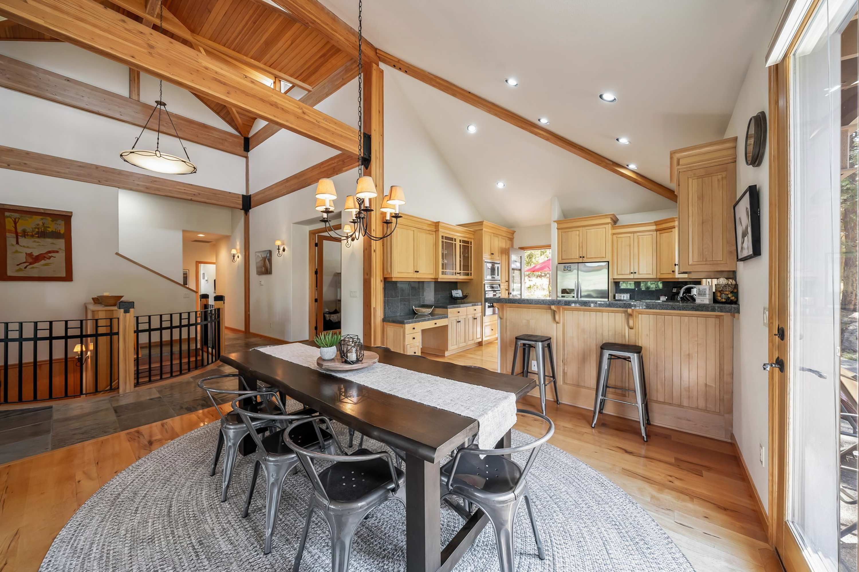 A spacious kitchen with wooden beams, a dining area with a table and chairs, and a kitchen island with stools.