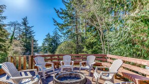 Una terraza con sillas Adirondack, una chimenea y una barandilla de madera.