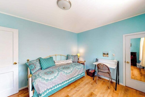 A bedroom with a bed, a desk, and a chair.