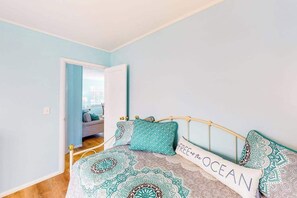 A bedroom with a bed, a door leading to another room, and a view of a cityscape through the door.