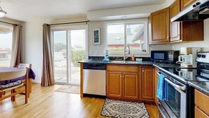 A kitchen with wooden cabinets, a dishwasher, a microwave, and an oven. - Experience Comfort and Serenity by the Sea, Dog Friendly with AC, & Patio (Yachats)