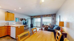 Un espacio habitable compacto con cocina, comedor y un balcón.