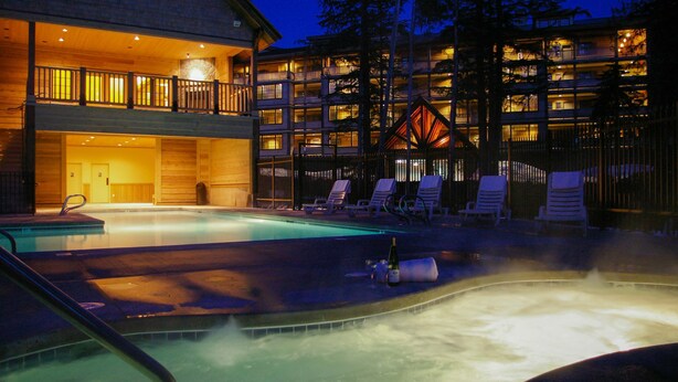 Ett hotell med en swimmingpool, solstolar och en bubbelpool.