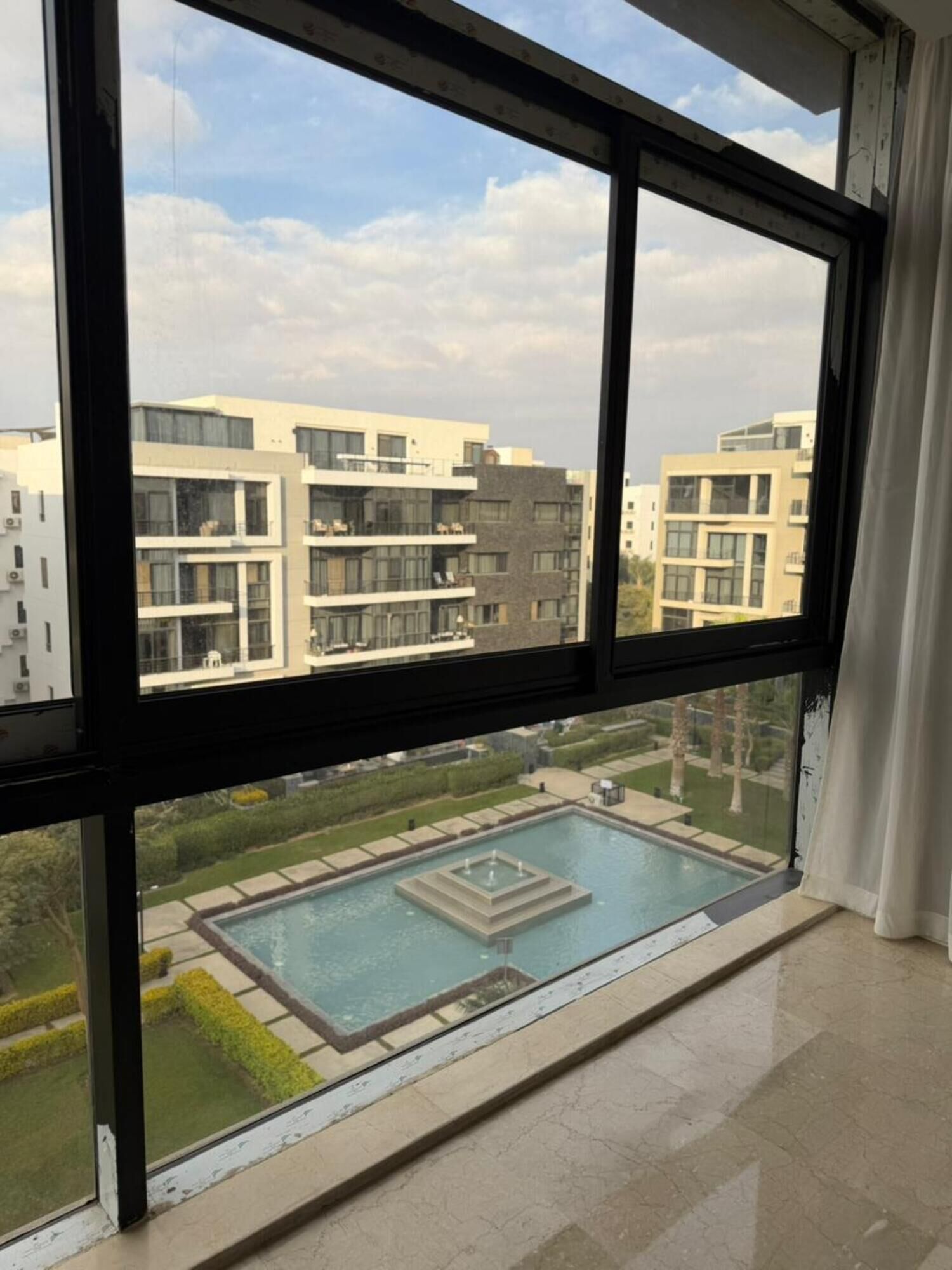 Een modern gebouw met een zwembad en uitzicht op andere gebouwen.