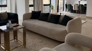 Una sala de estar moderna con sofá, sillones, una mesita de centro y un comedor con sillas y una mesa.