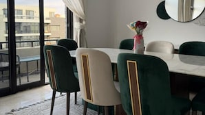 Un comedor con una mesa, sillas, un jarrón con flores y vistas a través de un ventanal.