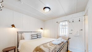 Makuuhuone, jossa on sänky, yöpöytä ja ikkuna, jossa on verhot.