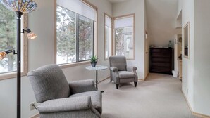A hallway with two armchairs, a floor lamp, and large windows. - Golf course-view townhome with private hot tub & SHARC access (Sunriver)