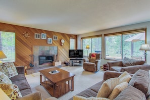 A living room with a fireplace, television, and large windows.