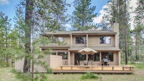 A two-story house with a deck, large windows, and a chimney. - Cabin with Private Hot Tub Near the Deschutes River - Free SHARC access (Sunriver)