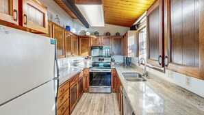 Una cocina con armarios de madera, un refrigerador de acero inoxidable, un microondas, un horno y un lavabo.