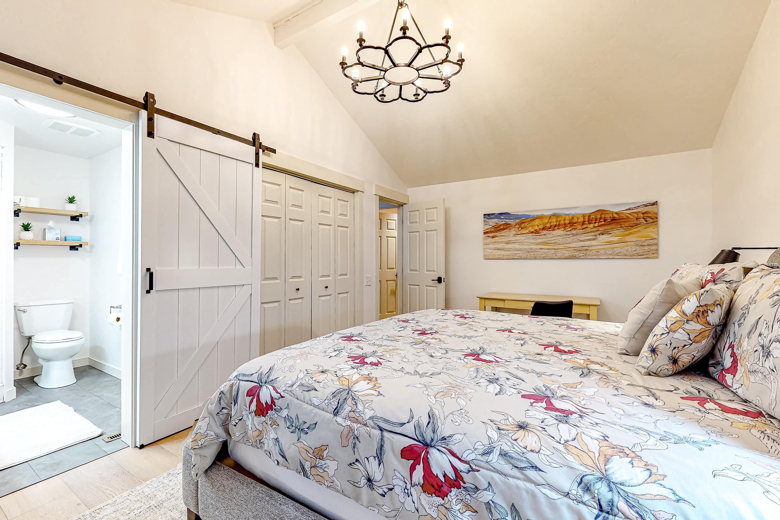 Ein Schlafzimmer mit Bett, einer Kristallleuchtre, einer Schiebetür und einem Gemälde an der Wand.