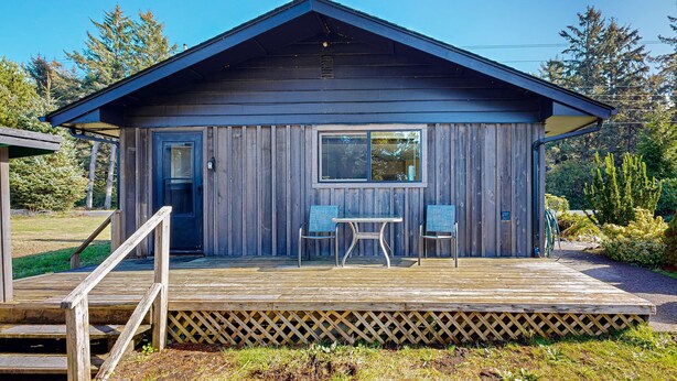 Eine Holz-Blockhütte mit Veranda, zwei Stühlen und einem Tisch.